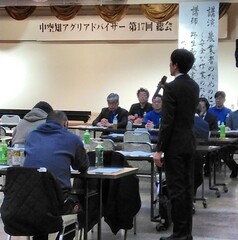 大勢の参加者の前で新規認定者が挨拶をする様子